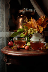 Autumn evening. Fragrant tea in glass cups and a bouquet of autumn leaves in a jug.