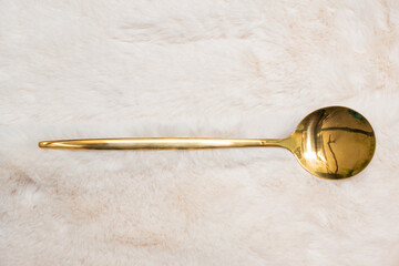 gold spoon on white fur background texture