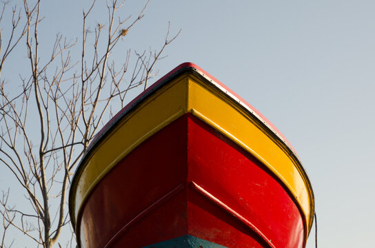 La prua di una barca rossa e gialla tirata in secca per la manutenzione vista dal basso