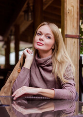 Portrait of a beautiful blonde woman in a cafe outdoors in autumn
