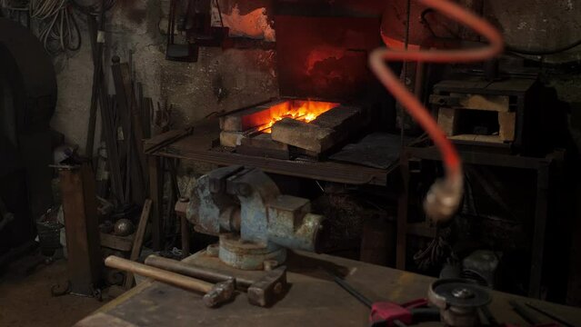 An incandescent metal product on an anthracite coal fire. The blacksmith is stirring the burning coals in the fire in the forge.
