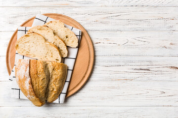 Freshly baked bread slices on cutting board against white wooden background. top view Sliced bread