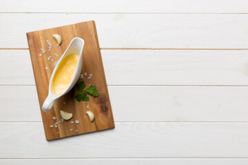 Gravy boat with tasty cheese sauce on table background. top view