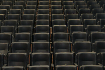 Theater auditorium with emphasis on the black chairs and wooden sides, all the same giving continuity and lines.