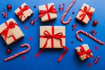 Obraz premium Christmas kraft gifts box with ribbon on colored background. Cozy Christmas still life, birthday or new year