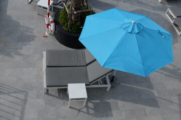 Blue umbrellas and gray sunbeds by the sea for tourists.