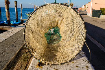 Una nassa per la pesca stesa ad asciugare al sole lungo una banchina a Pellestrina, isola della...