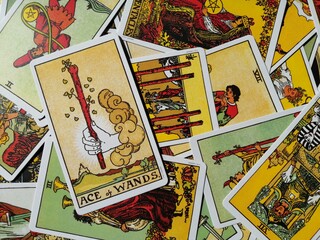 Picture of the Ace of Wands tarot card from the original Ride Waite tarot deck with mixed tarot cards in the background