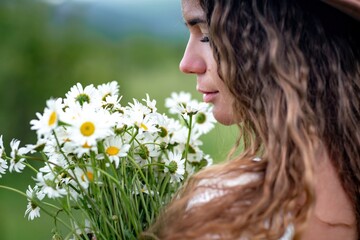 A middle-aged woman holds a large bouquet of daisies in her hands. Wildflowers for congratulations