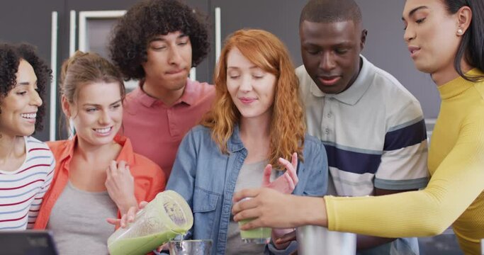 Happy group of diverse friends preparing healthy drink in kitchen together
