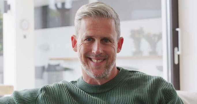 Video portrait of senior caucasian man smiling and laughing to camera indoors