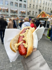 hot dog sandwich with mustard sauce against people on street