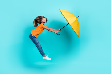 Side profile photo full body length of charming little carefree excited preteen girl air jump windy hold parasol enjoy isolated on aquamarine color background © deagreez