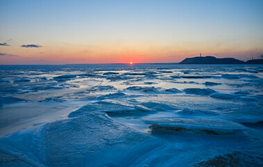 Aerial view of sunset over the frozen sea. Winter landscape on seashore during dusk. View from...