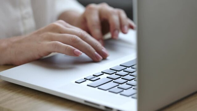 Freelancer working on a laptop from home, female hands in frame