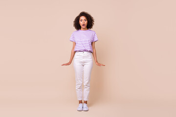 Fototapeta na wymiar Full size photo of nice lovely girl dressed striped t-shirt white trousers sneakers impressed reaction isolated on beige color background