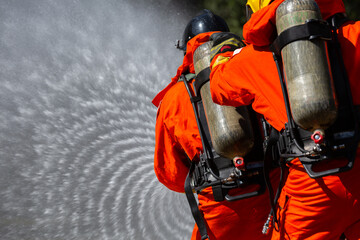 Firefighter on duty firefighting, Asian fireman spraying high pressure water, Fireman in fire fighting equipment uniform spray water from hose for fire fighting.