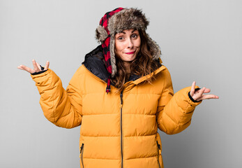hispanic pretty woman feeling puzzled and confused and doubting. wearing an anorak. cold and winter...