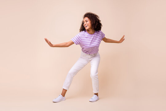 Full length photo of funny pretty lady wear violet t-shirt riding surf board isolated beige color background
