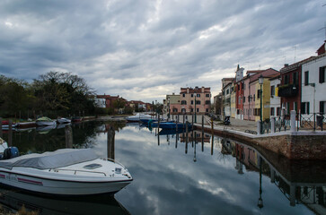 Un canale del piccolo borgo di Malamocco al Lido di Venezia in una giornata nuvolosa d'inverno con...