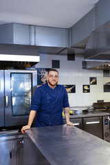 Young chef in his restaurant leaning against the plate preparation table