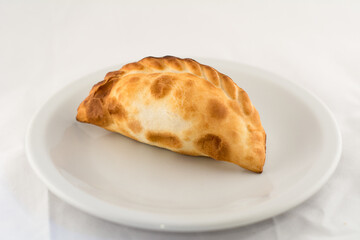 empanada argentina horneada sobre plato blanco