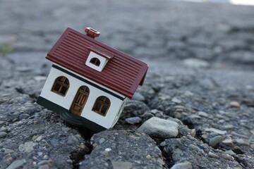 House model in cracked asphalt. Earthquake disaster - obrazy, fototapety, plakaty