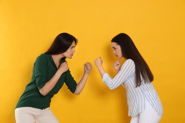 Young women ready to fight on orange background