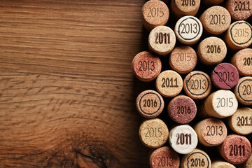 Flat lay composition with many wine corks with different dates on wooden table. Space for text