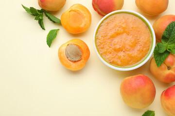 Apricot puree in bowl and fresh fruits on beige background, flat lay. Space for text