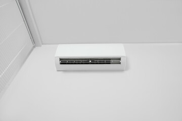 Modern air conditioner on white wall indoors, low angle view. Space text copy