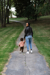 Black mother walking on sidewalk with biracial toddler