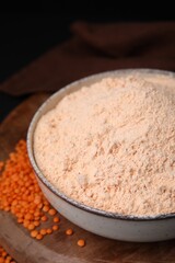 Bowl of lentil flour and seeds on wooden board, closeup