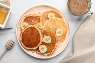 Tasty pancakes with sliced banana served on white marble table, flat lay