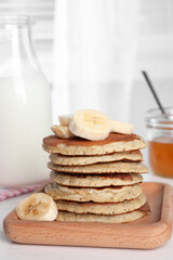 Fototapeta na wymiar Plate of banana pancakes with honey and milk on white wooden table