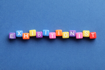 Word EXHIBITIONIST made with colorful cubes on blue background, flat lay