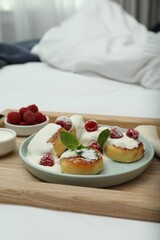 Tasty breakfast served in bedroom. Cottage cheese pancakes with fresh raspberries, mint, sour cream and icing sugar on wooden tray