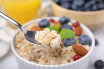 Spoon of oatmeal against blurred background, closeup