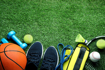 Set of different colorful sports equipment on green grass, flat lay. Space for text
