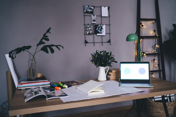 Opened netbook and stationery with plants on table