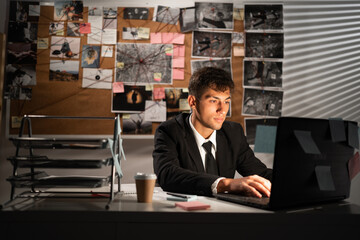 Private detective looking in internet some information, working in his office, processing evidence