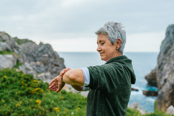 older woman with gray hair, wearing sportswear, looking at her sports activity marks as well as her...