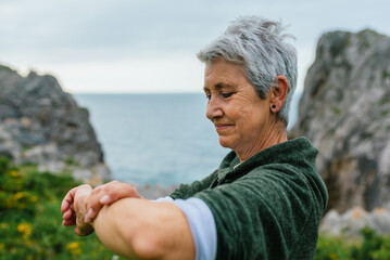 older woman with gray hair, wearing sportswear, looking at her sports activity marks as well as her...