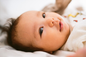 close up of cute smiling latino baby girl in bed with morning light. Waking up in bed. healthy hispanic baby with warm natural light