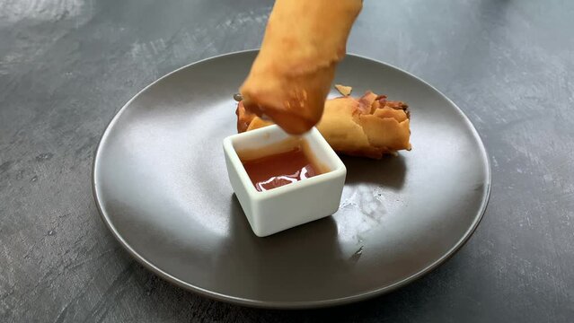 Dipping a Spring roll in Sweet and Sour Sauce