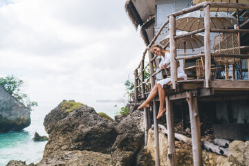 Happy woman enjoying vacation on summer terrace near sea