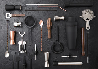 Various cocktail bar utensils set. Strainer,shaker,jigger,straw,juicer,muddler,wine opener on black stone background.