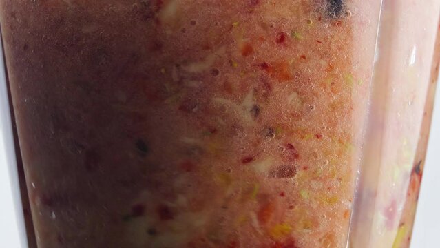 Closeup rotation blending fruits berries inside blender in super slow motion.