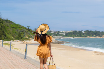 Travel woman with straw hat and walk along the sand beach