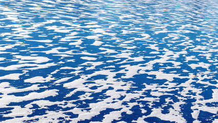 Winter background with blue ice of the river covered with white snow